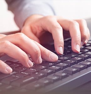 Hands typing on a black keyboard